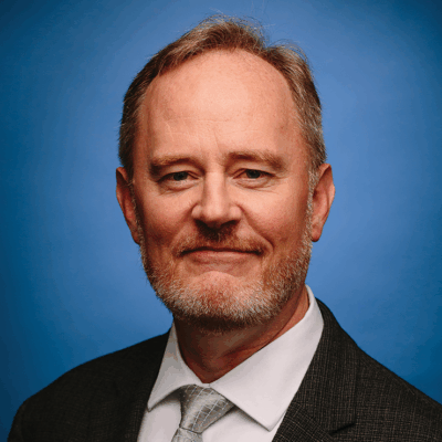ACLU of Iowa Director Mark Stringer is pictured in front of a blue background.