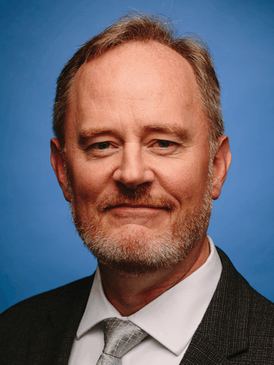 ACLU of Iowa Director Mark Stringer is pictured in front of a blue background.