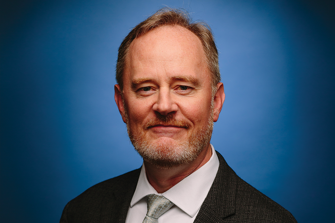 ACLU of Iowa Director Mark Stringer is pictured in front of a blue background.