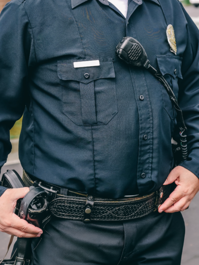 A police officer stands with a hand on his gun.