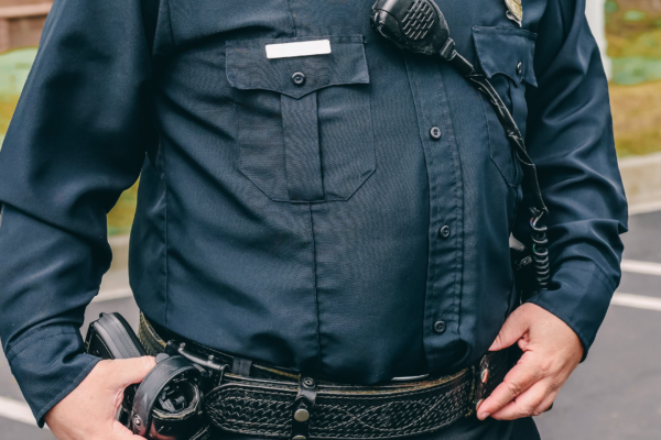 A police officer stands with a hand on his gun.